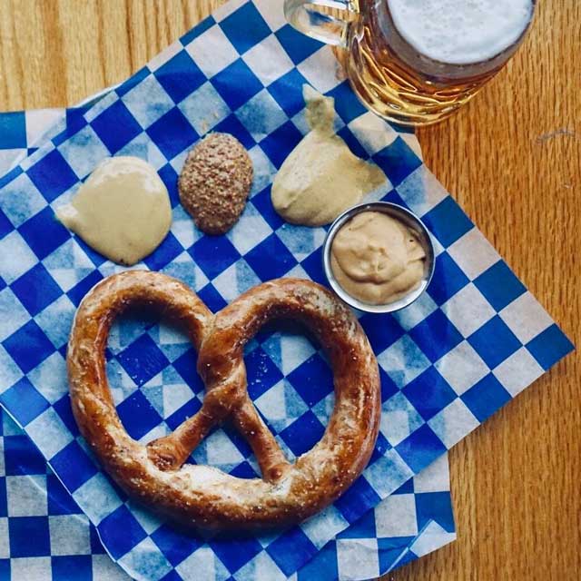 Pretzel, mustards and stein of beer.